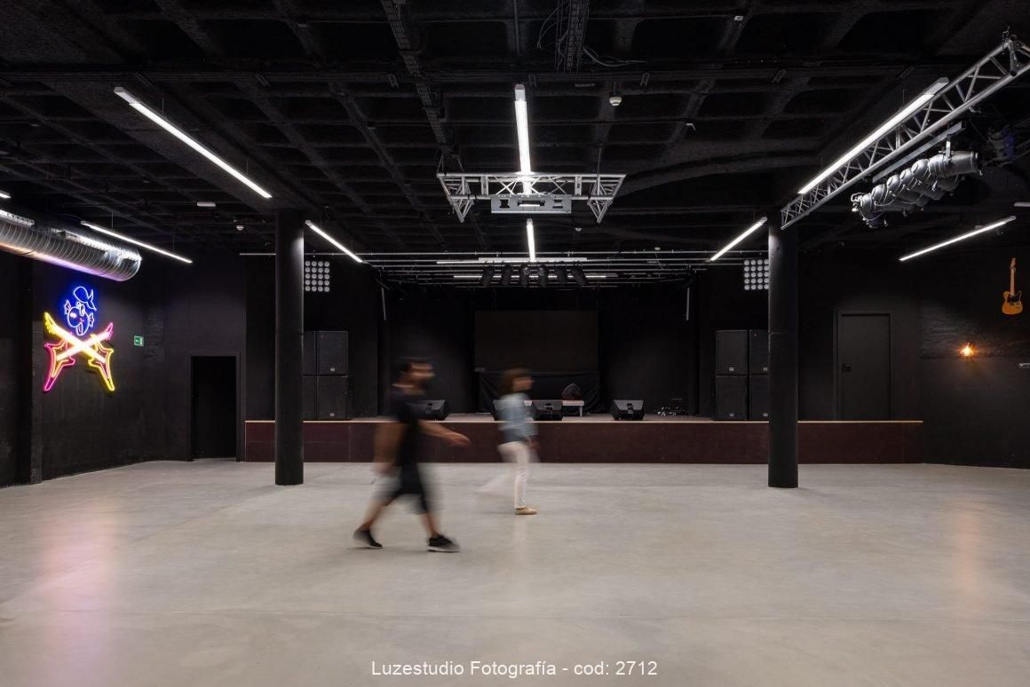 dos personas pasando delante del escenario de la sala de conciertos
