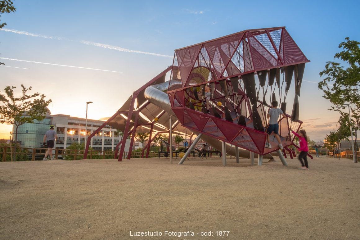 niños entrando en la boca del dinosaurio jugando en parque infantil trex al atardecer
