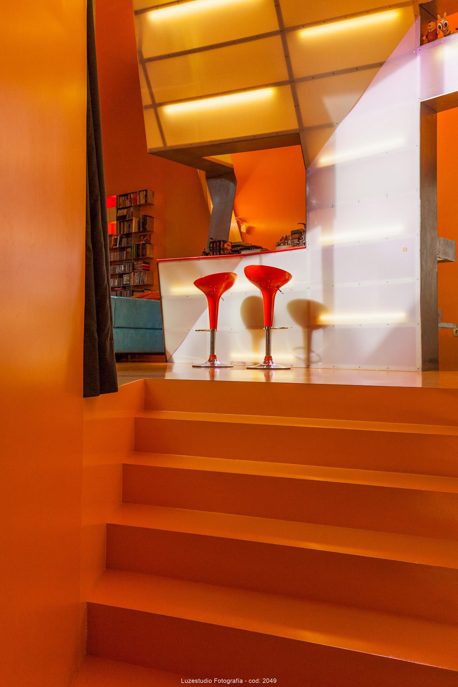 fotografía de interiores escaleras de subida suelo naranja con vistas a barra y salón en casa levene eduardo arroyo
