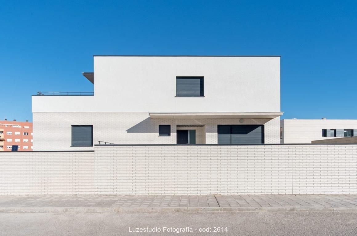 fachada calle de una casa con ventanas cerradas pared blanca y muro de ladrillo crema en guadalajara fotografo de arquitectura