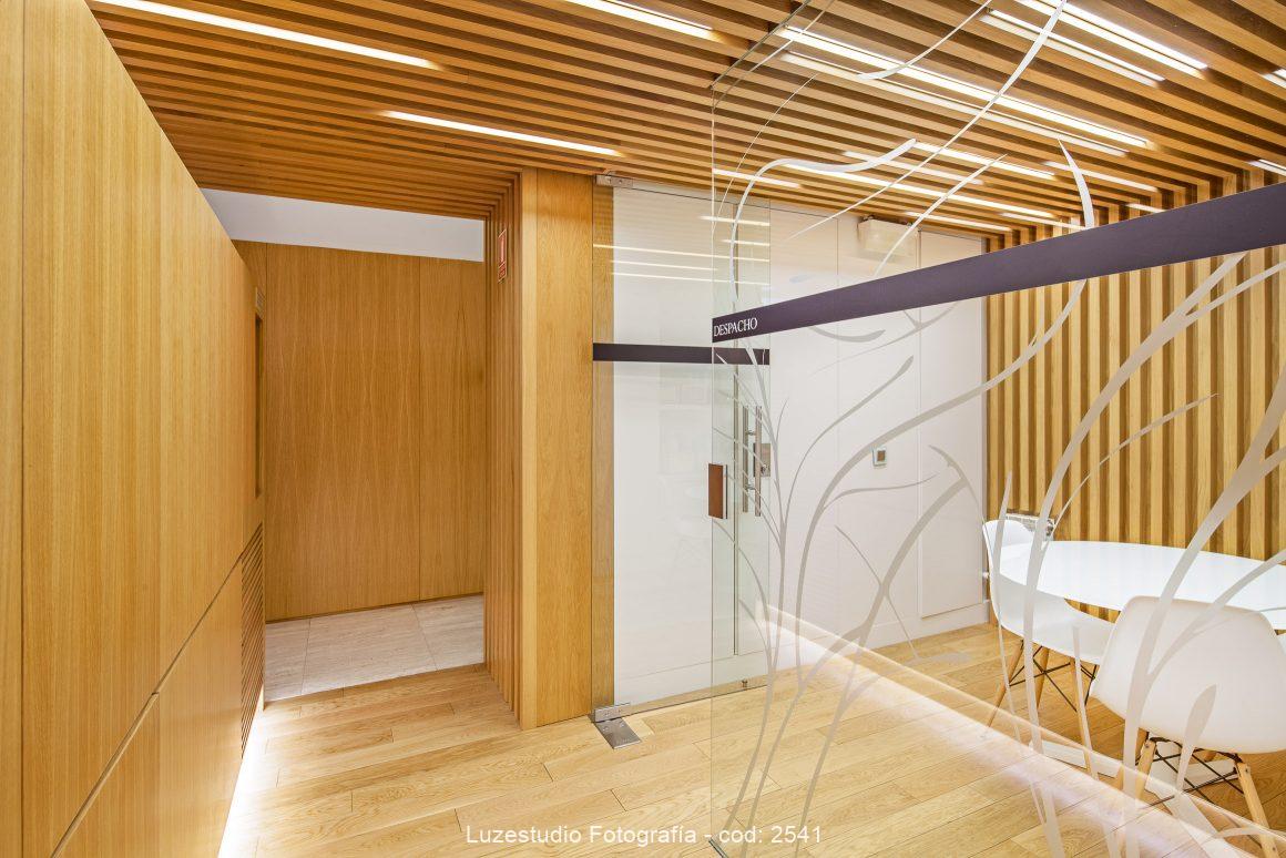 fotografía de interior diseño clinica con paneles de madera y despacho con paredes transparentes