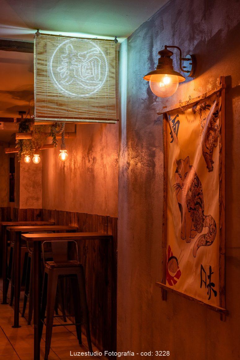 entrada de restaurante japonés con cuadro de tela y mesasa altas