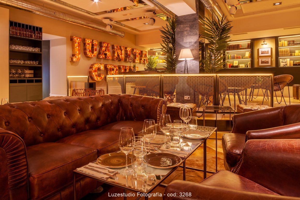 mesa puesta frente a sofa chester en el interior del restaurante de diseño de grupo larrumba