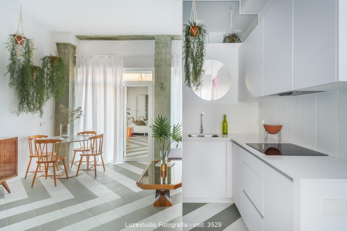 fotografía de interiores cocina blanca y salón reflejado en gran pared espejo diseño tatiana garcia bueso