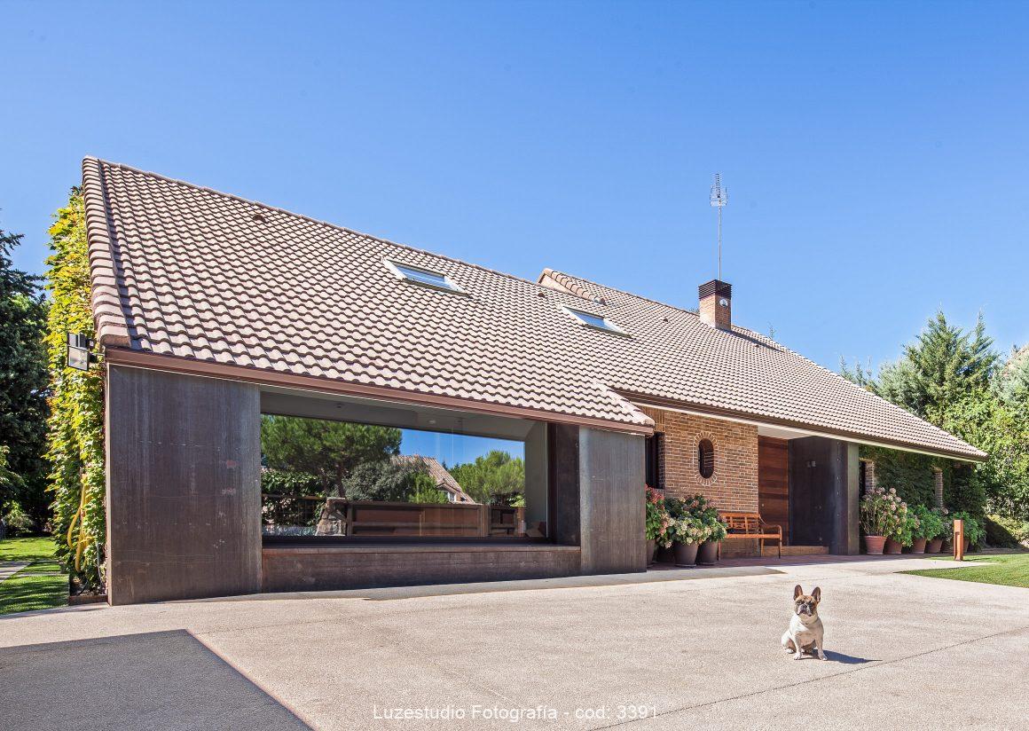 perro delante de una casa con tejado inclinado de tejas y cielo azul fotografo de arquitectura madrid