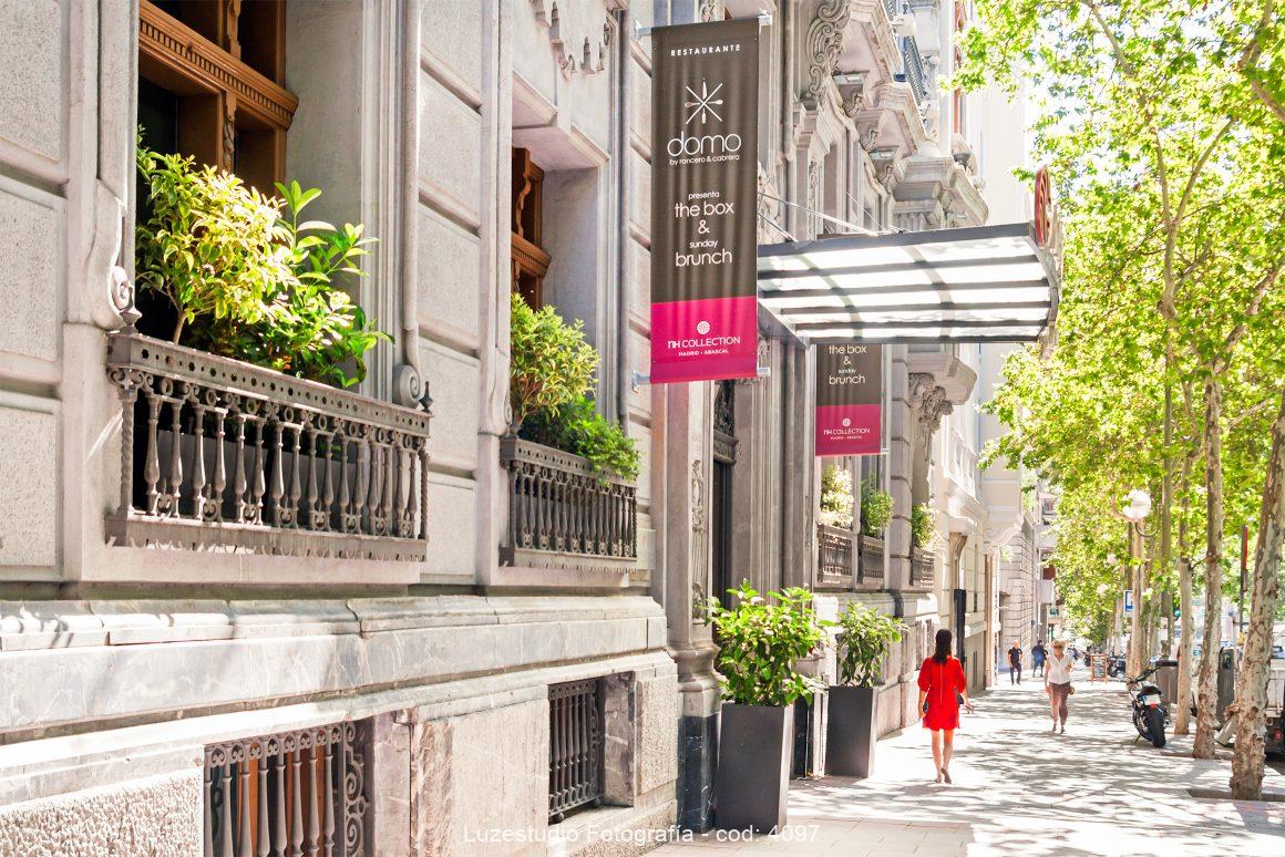 mujer con vestido rojo caminando por la calle jose abascal en madrid frente a hotel nh