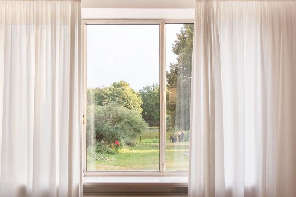 ventana con cortinas blancas y vistas al jardín de lemke haus en berlin