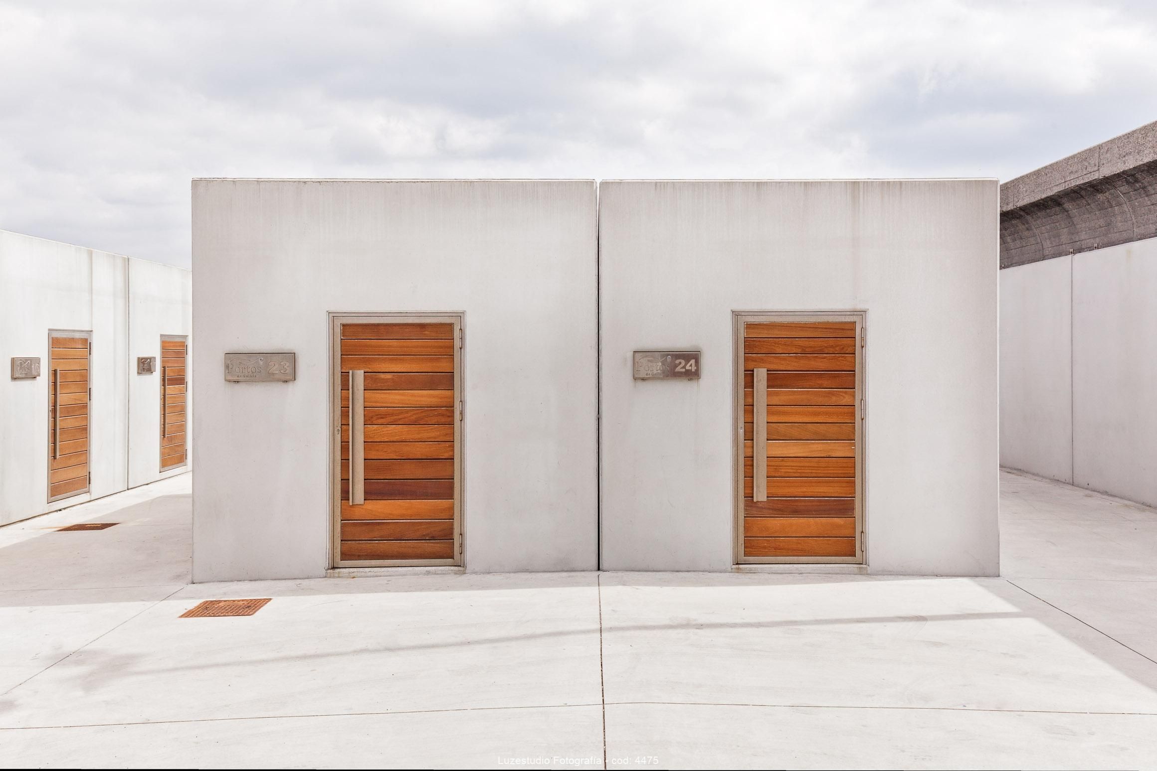 reportaje de arquitectura frontal de almacenes de hormigón con puertas de madera diseño creus y carrasco