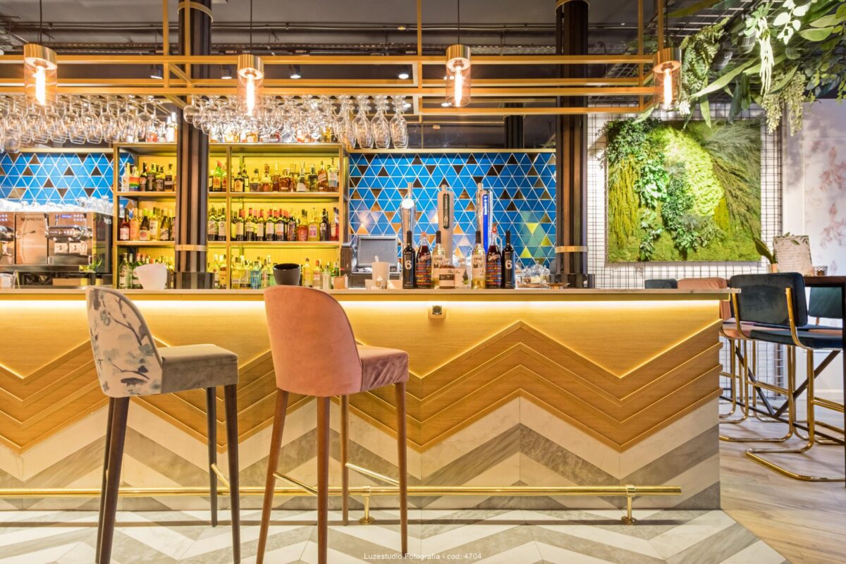 barra de madera y marmol con iluminación led pared azulejo azul y jardín vertical en restaurante fotografiado por fotógrafo de interiores
