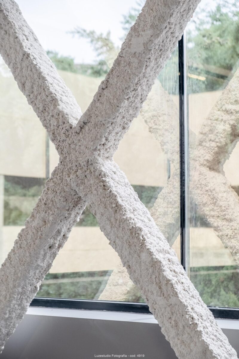 detalle de estructura de columna en forma de x delante de cristal con vista al exterior