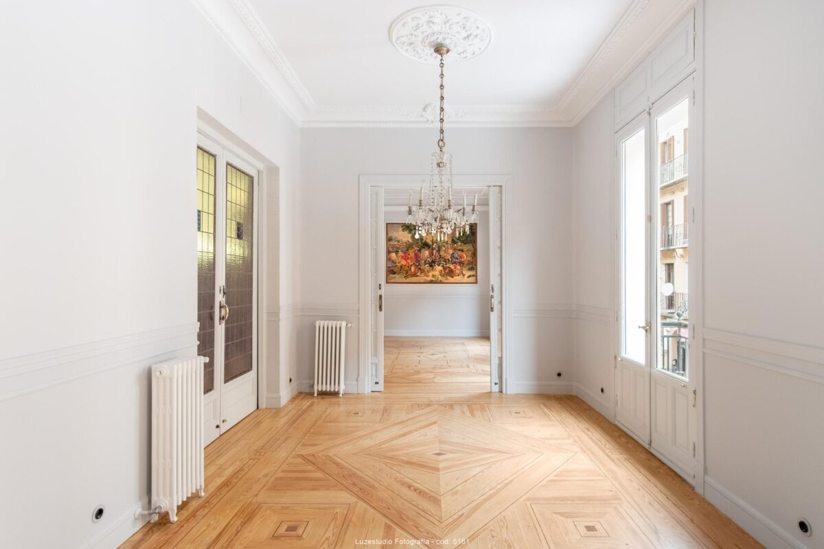 interior de salón reformado sin muebles con candelabro clásico y radiadores blancos