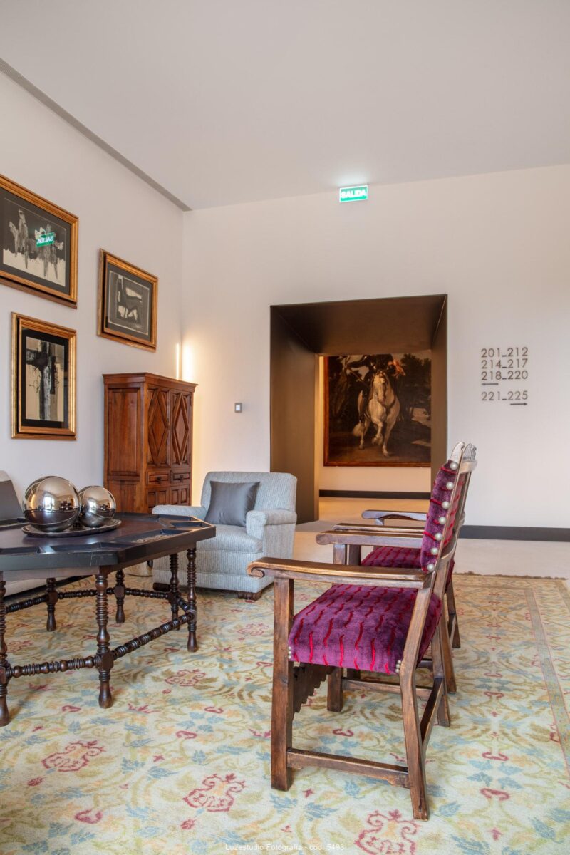 salón con obras de arte sillas de madera y alfombra en el parador de león
