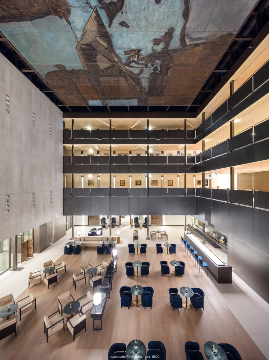 fotografía de arquitectura e interiores atrio Parador de León con cuadro de Lucio Muñoz en el techo pasillos con obras de arte y lounge con barra y mobiliario de sintra