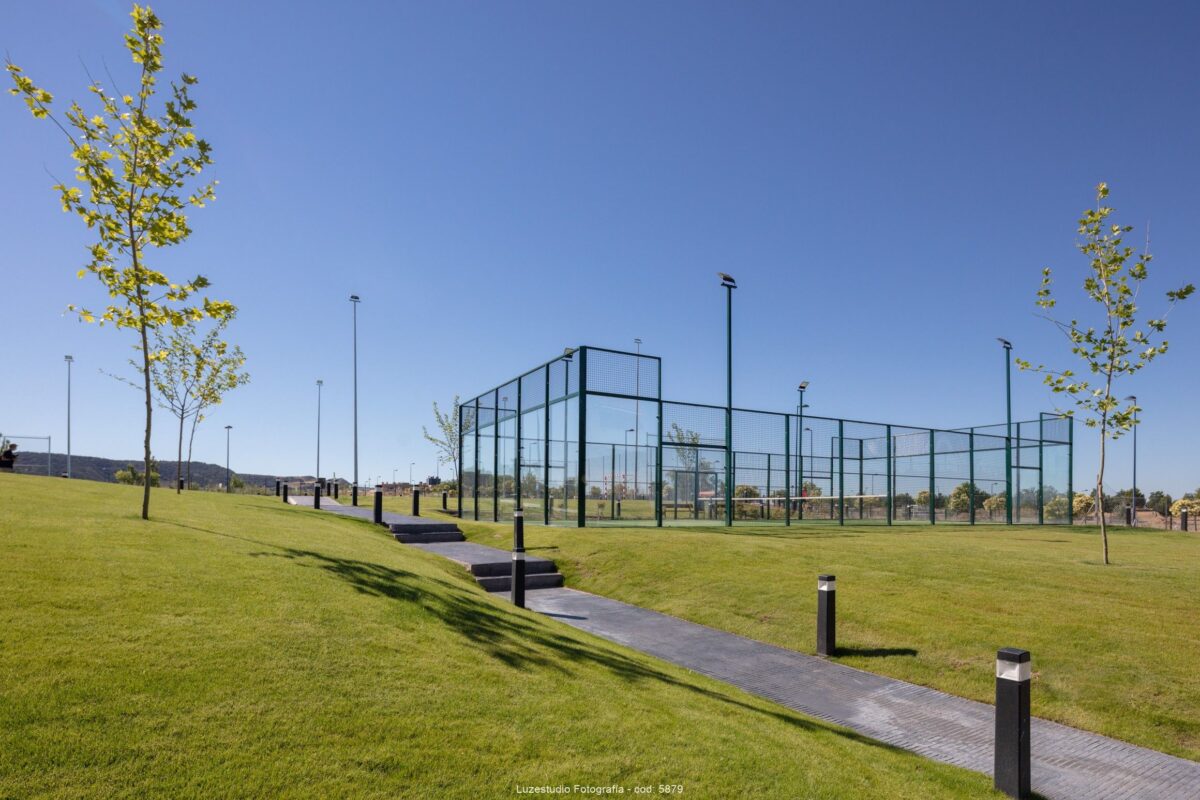 fotografía de pista de padel vallada en urbanización con cesped y arboles en madrid