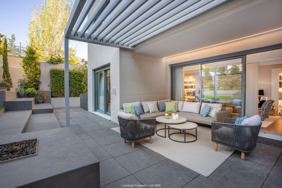 terraza con mobiliario de exterior en patio de chalet en madrid con vistas al salón iluminado