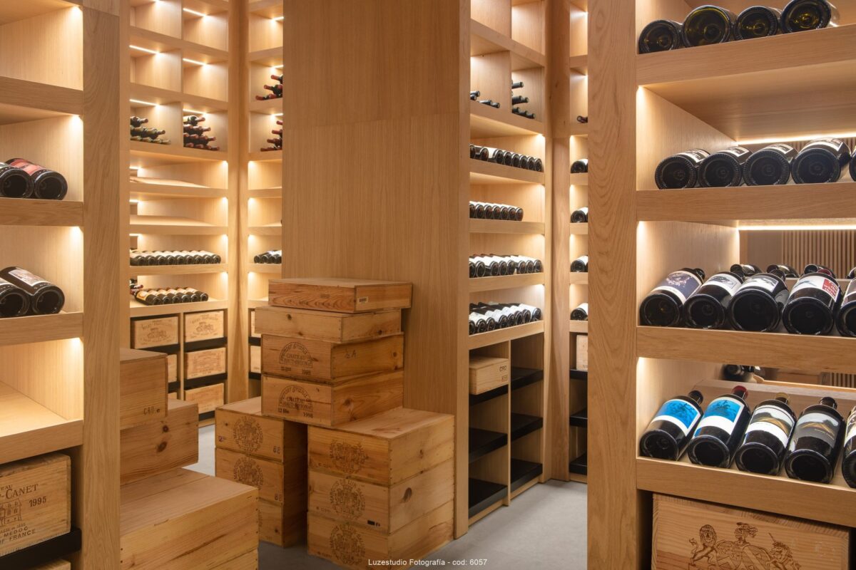 cajas con vino y estanterias de madera con botellas de vino en bodega de collecionista con refrigeración