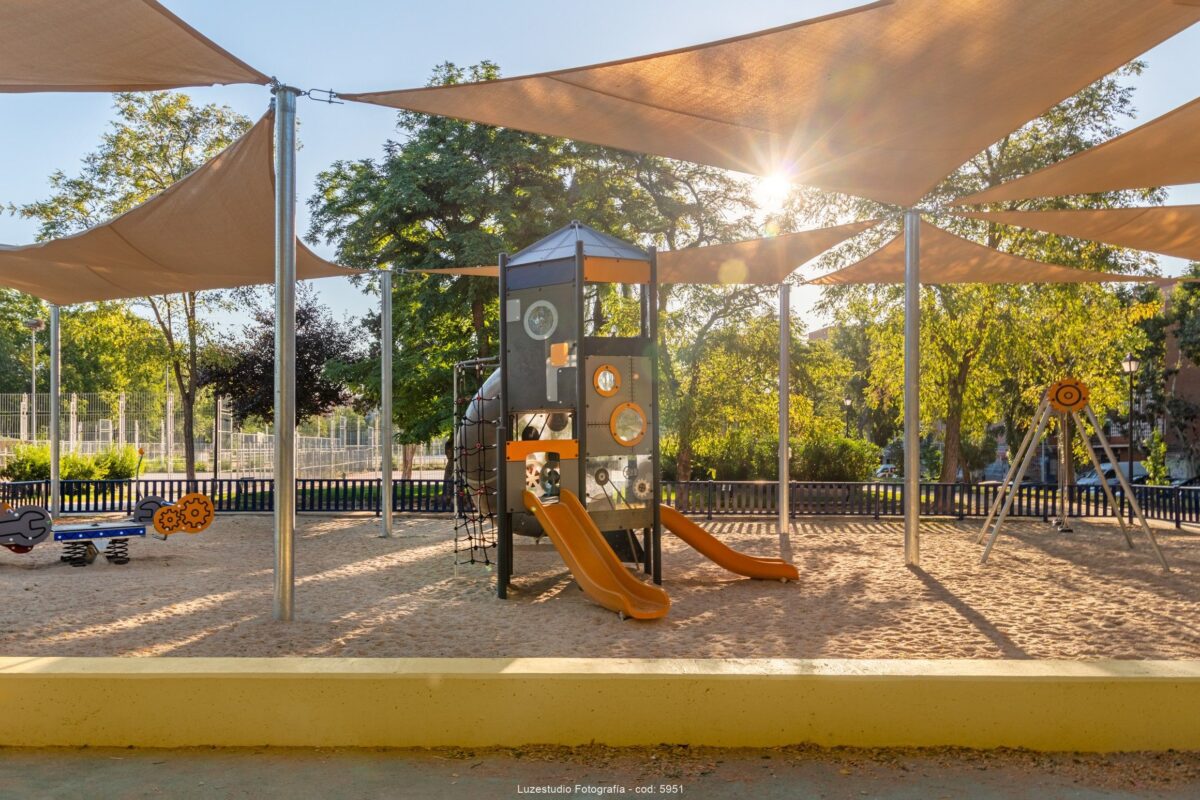 fotografía de parque infantil con el sol entrando entre las lonas encima de torre de juegos