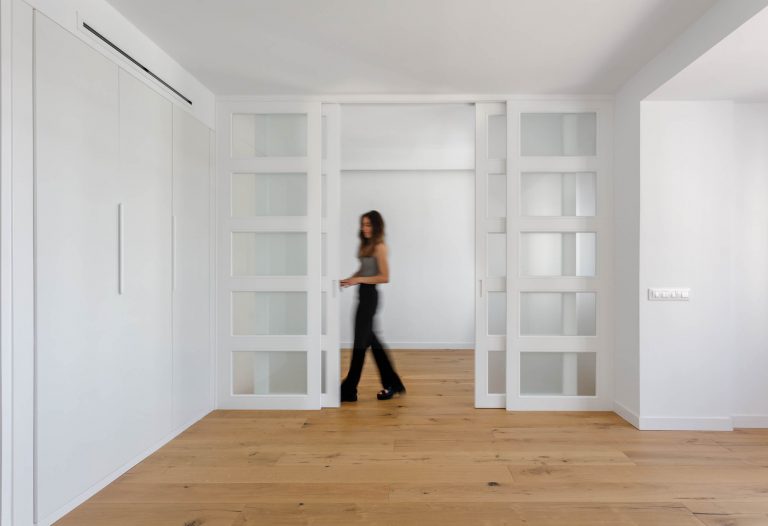 mujer abre puerta corredera blanca con vidrio en piso reformado en madrid fotografa alina banta