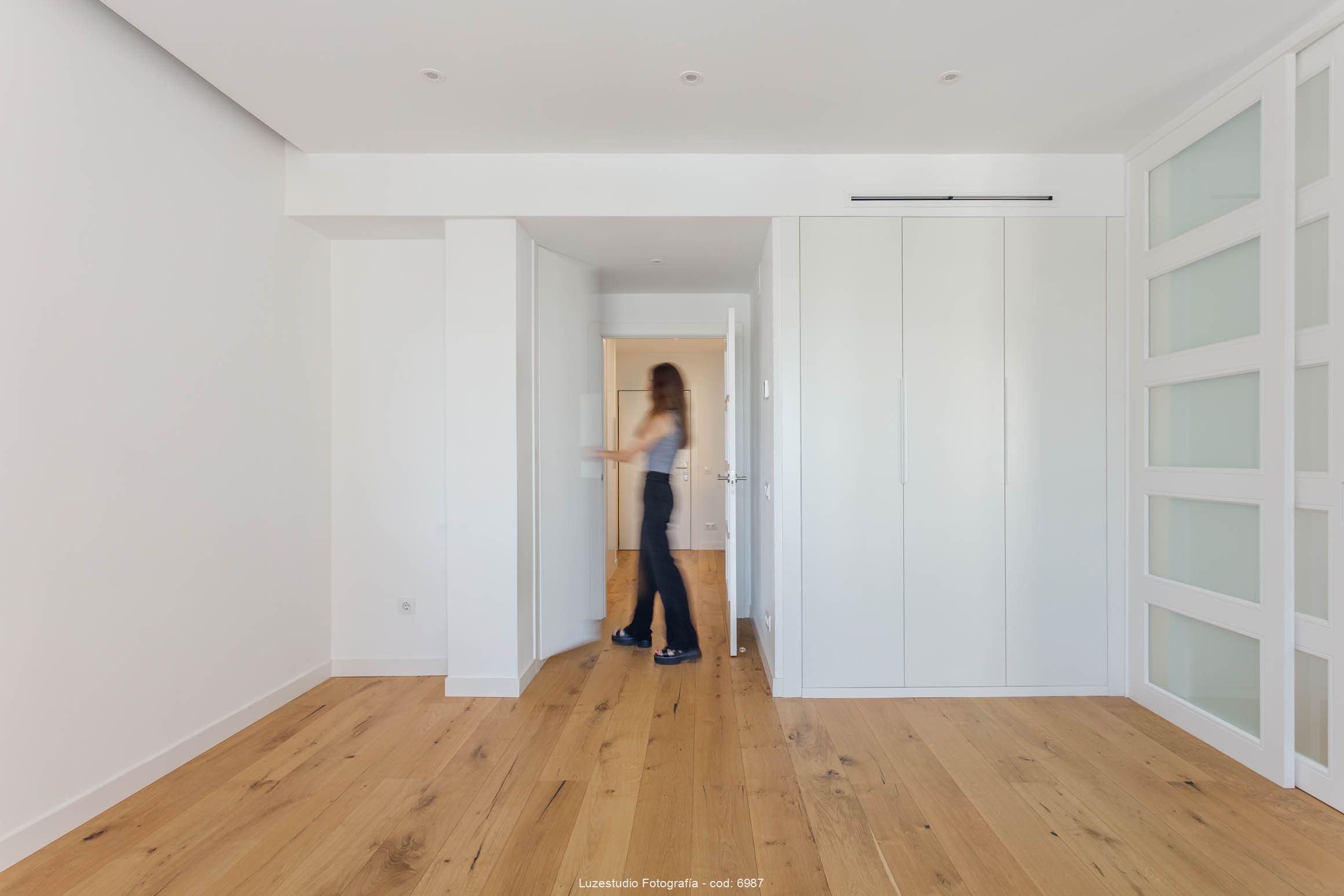 mujer abre la puerta de un armario blanco en sala de piso sin amueblar