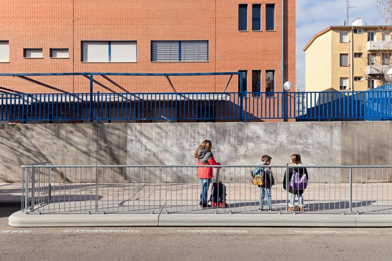 dos niñas y un niño con mochilas en plataforma de cemento ampliacion de acera frente a una escuela de madrid