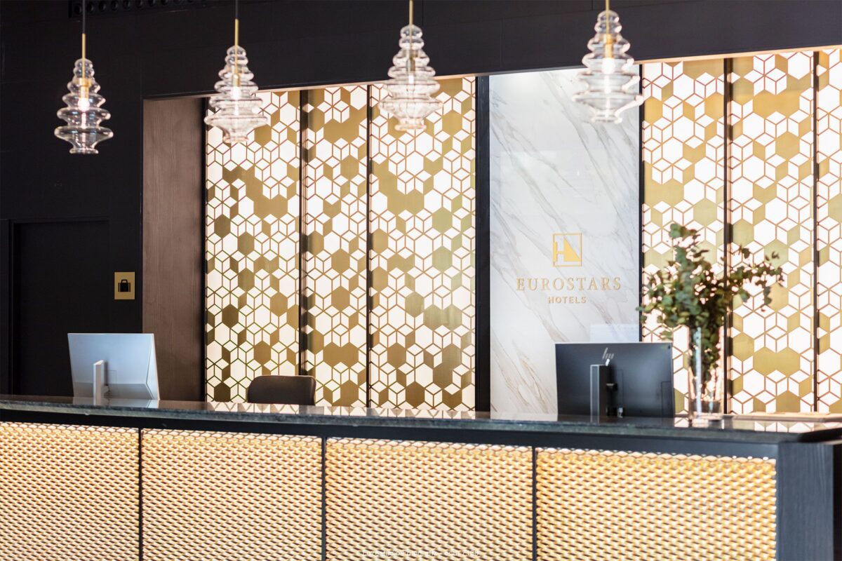 diseño de interiores recepción de hotel con luminarias de cristal y paneles en tonos dorados