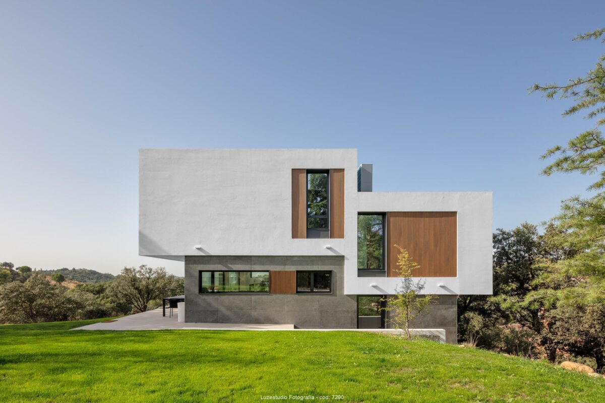 fachada de casa unifamiliar con planta alta y ventanas con laminas de madera rodeada de jardin