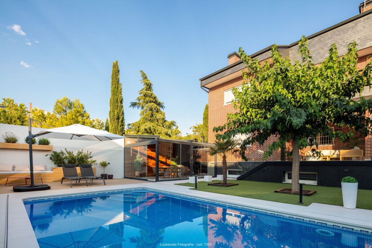 piscina en patio con cesped artificial y terraza de invierno cubierta en una vivienda unifamiliar