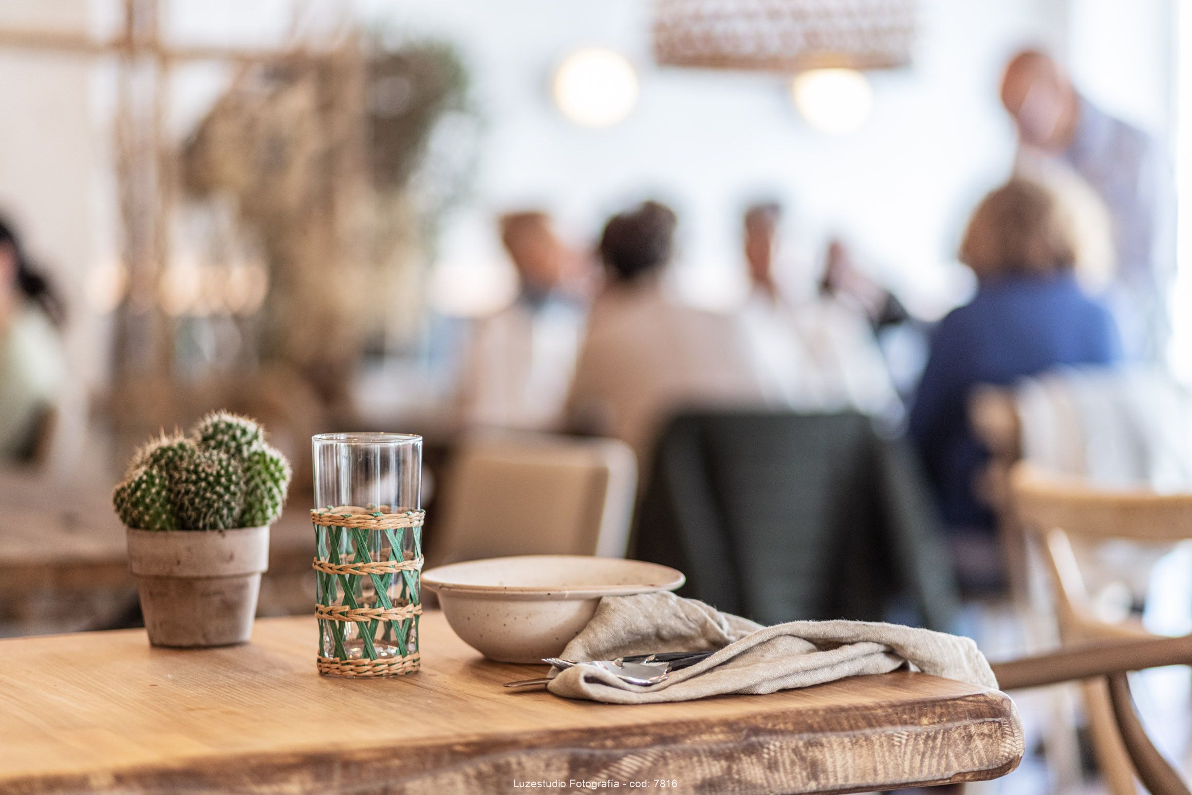 Fotógrafa de interiores alina banta reportaje interiorismo para francisco segarra (10) vajilla de fernando segarra en mesa de madera con fonde de gente comiendo en una cafeteria