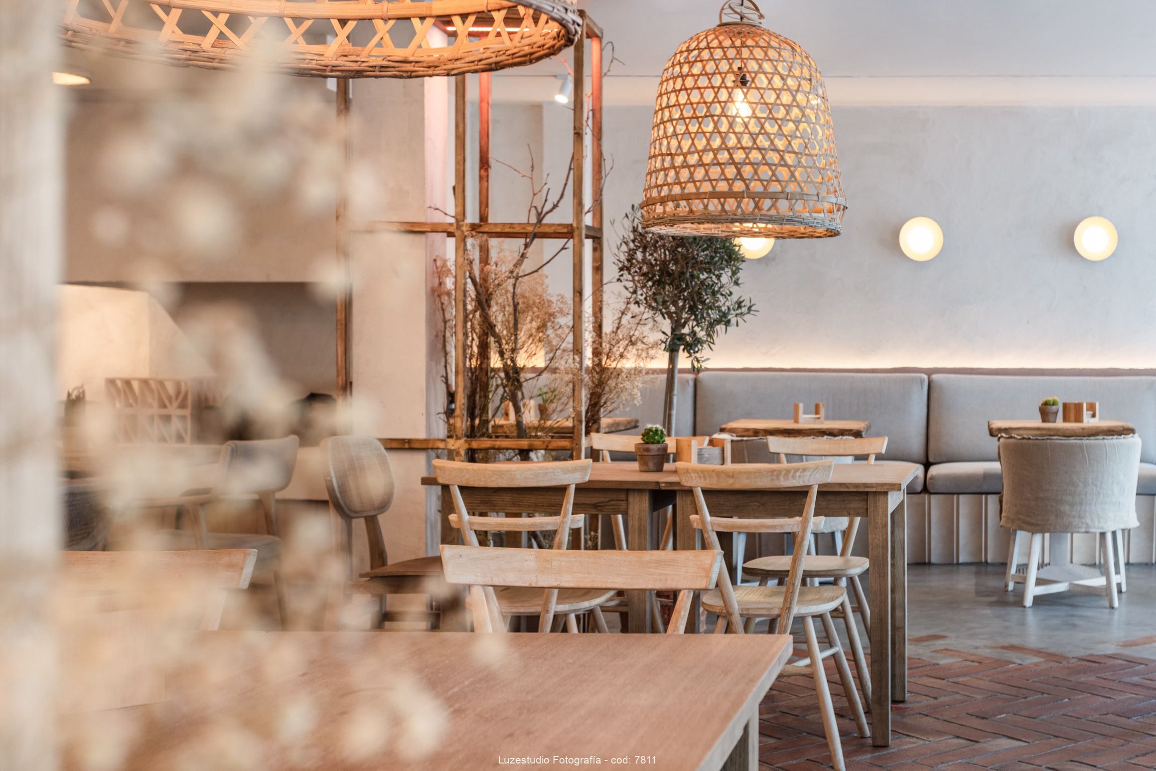 cafetería decorada en tonos cálidos con mobiliario de madera lamparas colgadas y flores desenfocadas en primer plano