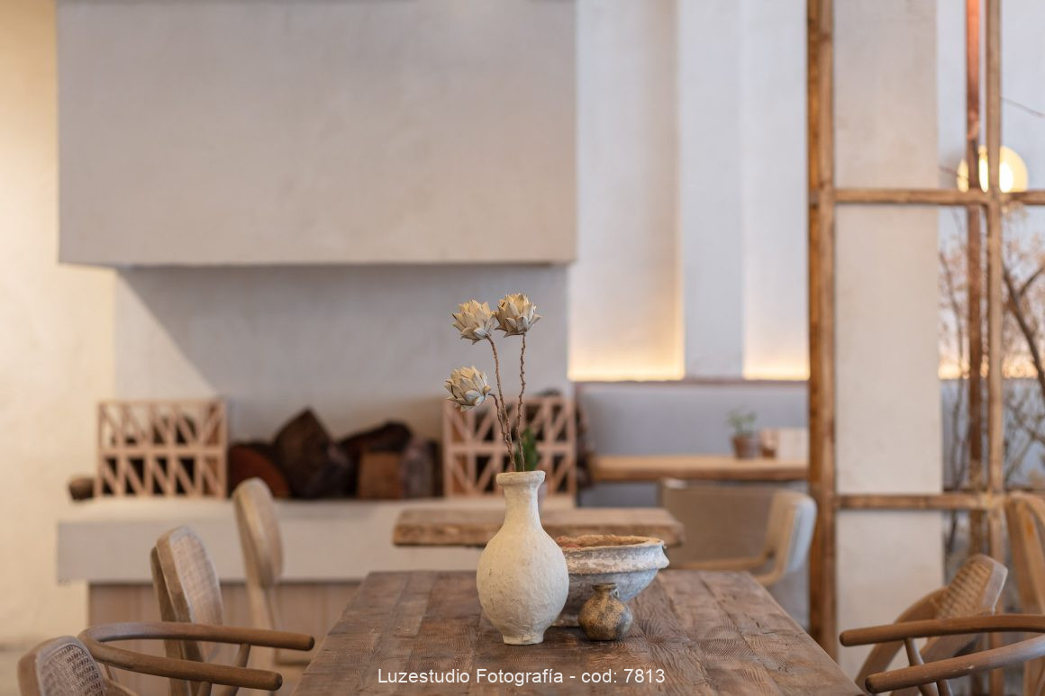 fotografía de chimenea revestida de microcemento con muebles de madera alrededor en cafeteria fotografiada por fotógrafa de interiores
