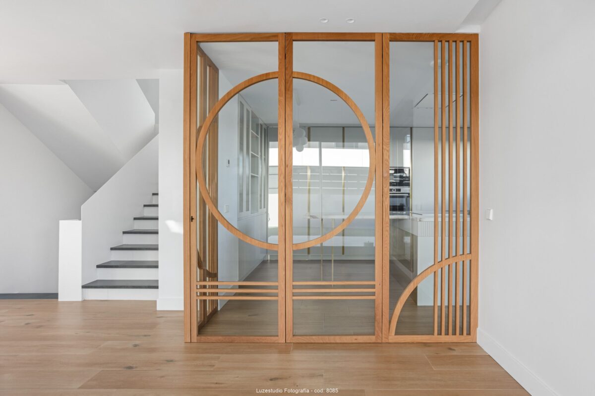 fotografía de interior puerta con perfileria de madera y cristal al lado de escalera con peldaños negros