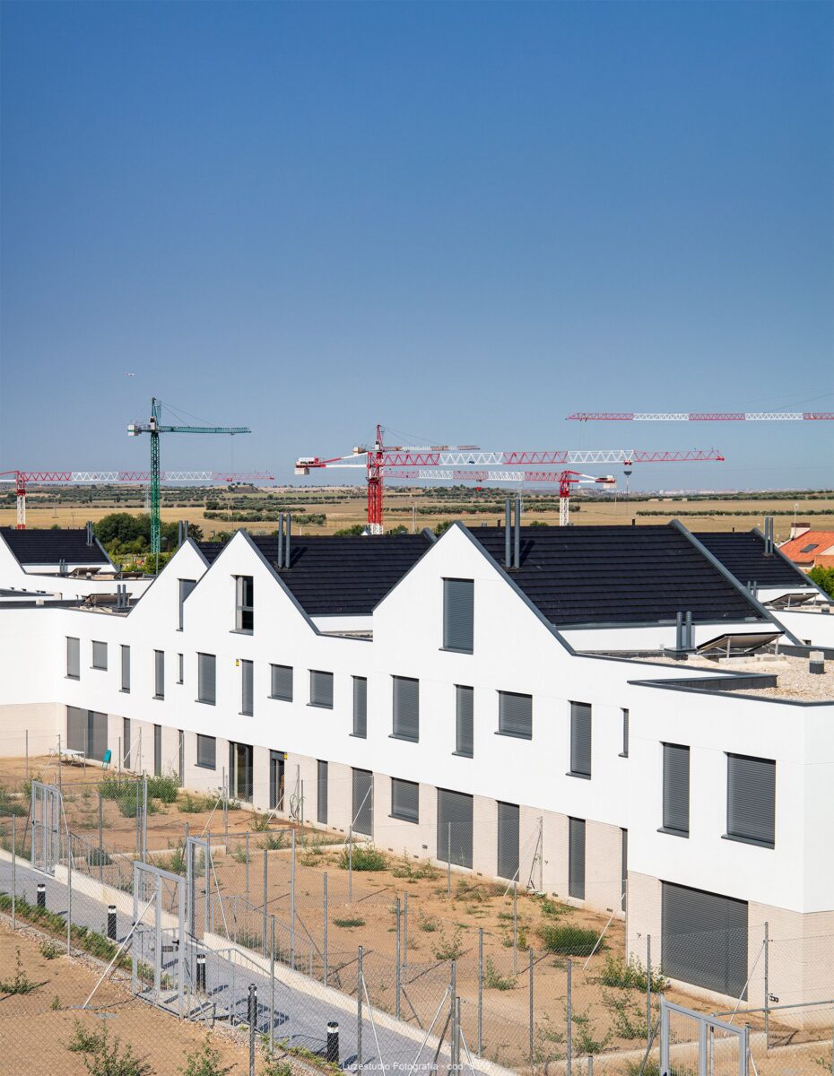 urbanización de chalets pareados con patios de tierra y gruas detras en villalbilla
