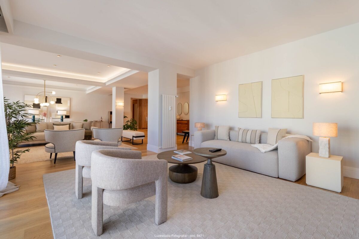 salón con sofa y butacas grises en piso con diseño de interiores minimalista con lamparas encendidas en reportaje fotografía de interiores