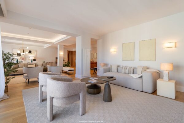 salón con sofa y butacas grises en piso con diseño de interiores minimalista con lamparas encendidas en reportaje fotografía de interiores