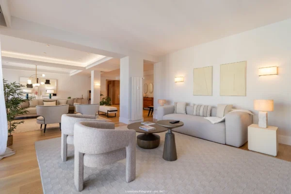 salón con sofa y butacas grises en piso con diseño de interiores minimalista con lamparas encendidas en reportaje fotografía de interiores