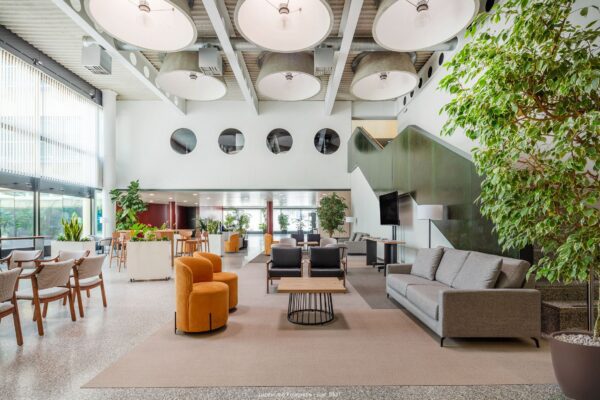 fotografía de interior zona de espera ayuntamiento con sofa mesas y sillas y techos altos