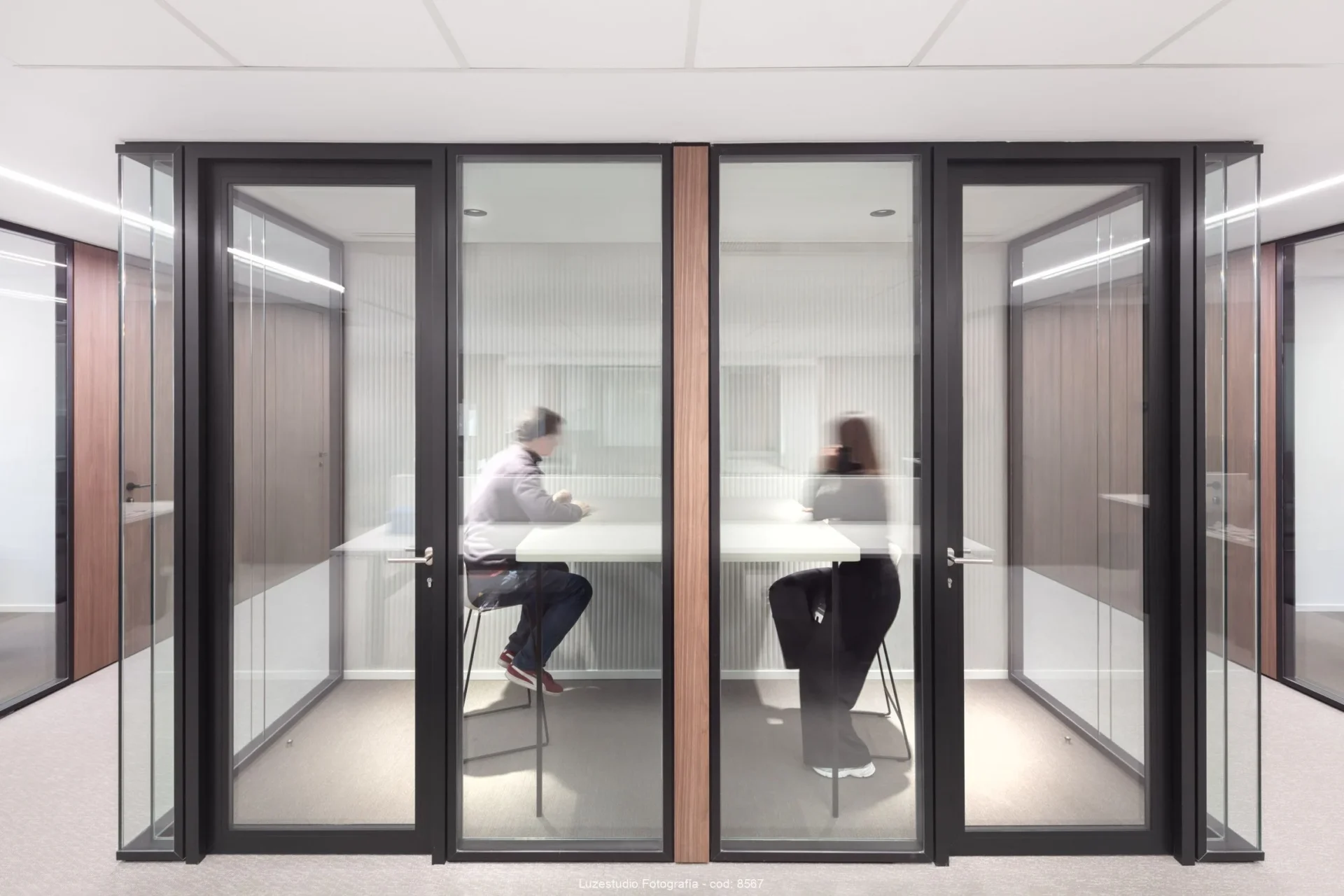 dos personas trabajando en cabinas insonorizadas en oficina de madrid