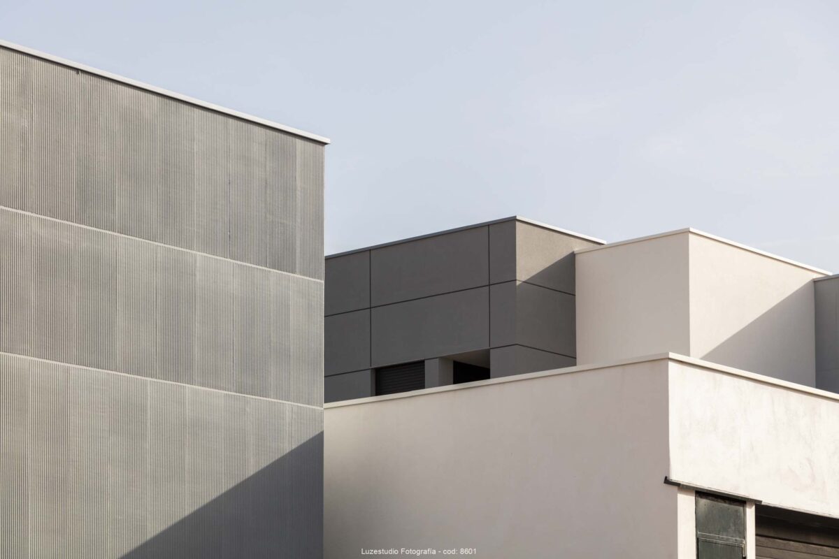 volúmenes de arquitectura residencial de color blanco roto y gris iluminados por el sol fotografa alina banta