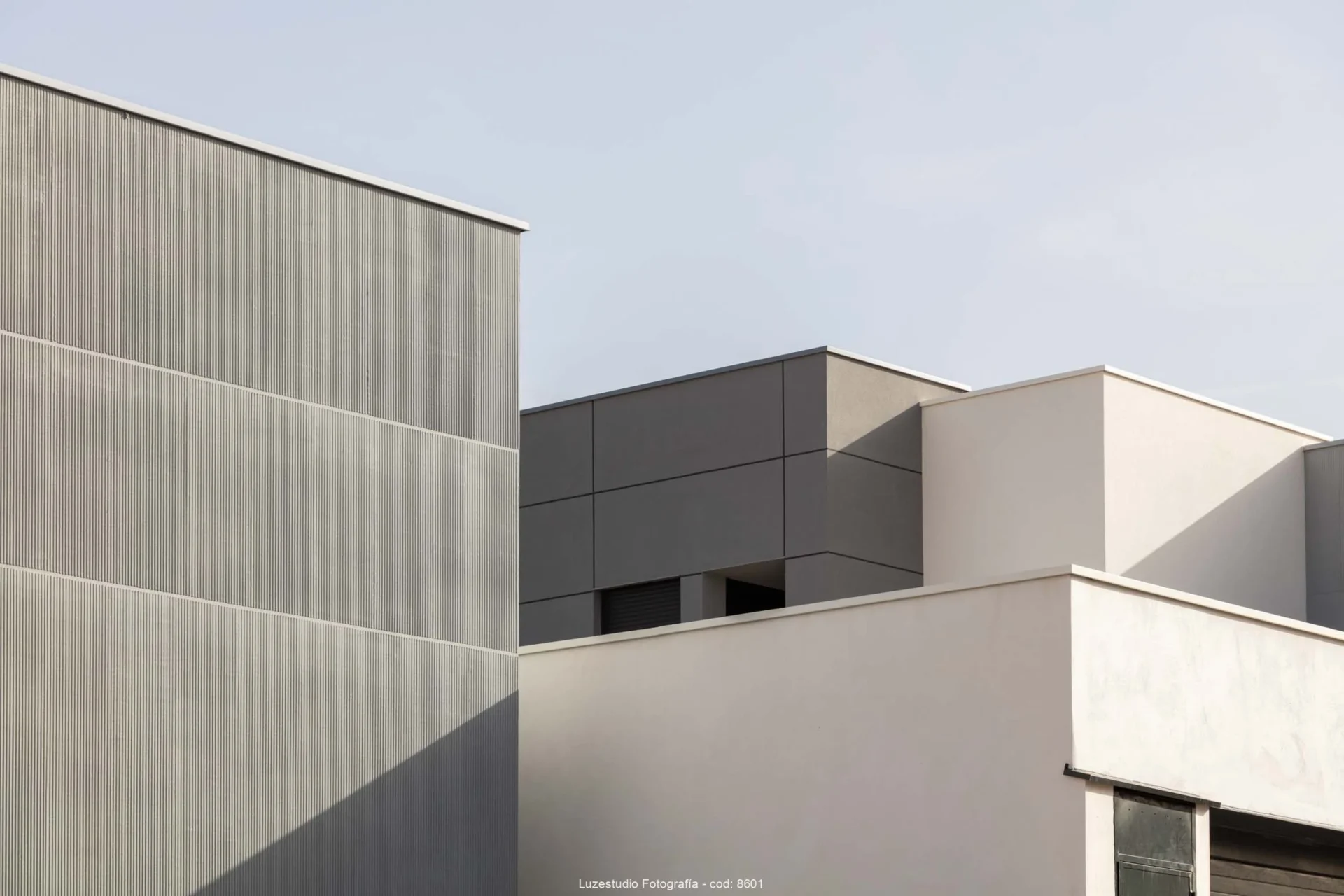 volúmenes de arquitectura residencial de color blanco roto y gris iluminados por el sol fotografa alina banta
