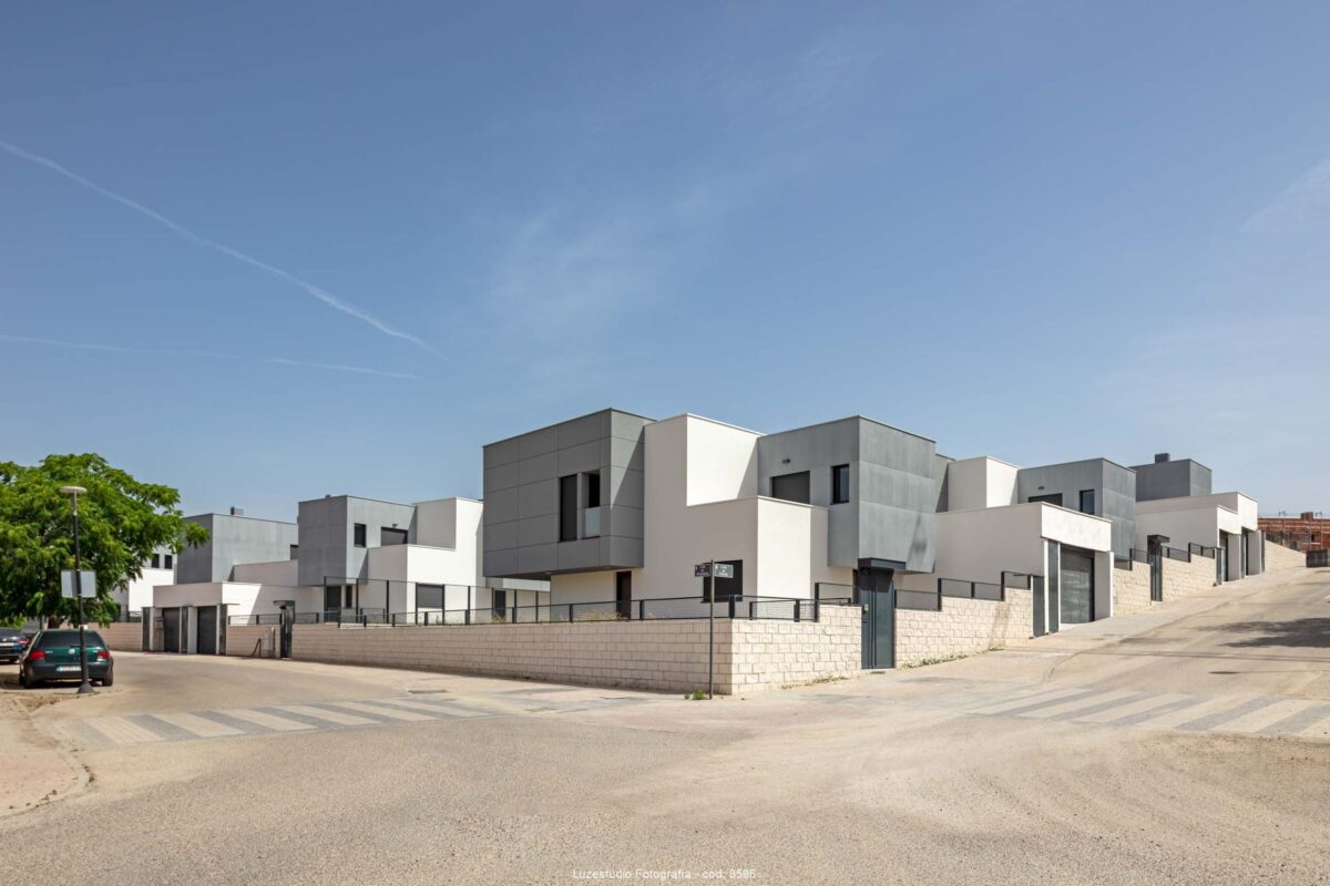 esquina de calle con chalets pareados con diseño de fachada minimalista en volumenes gris y blancos
