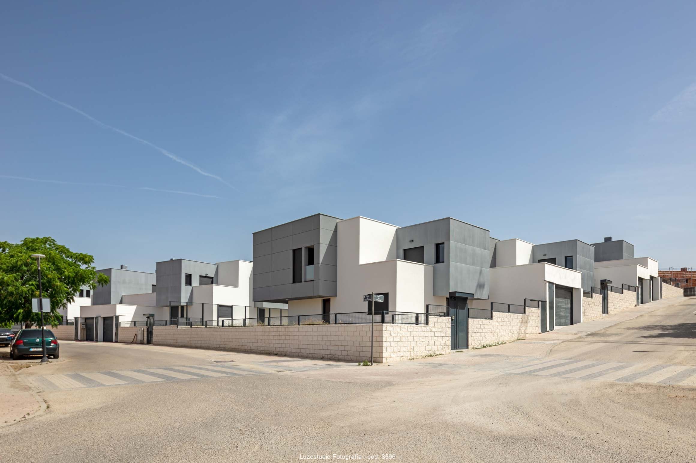 esquina de calle con chalets pareados con diseño de fachada minimalista en volumenes gris y blancos