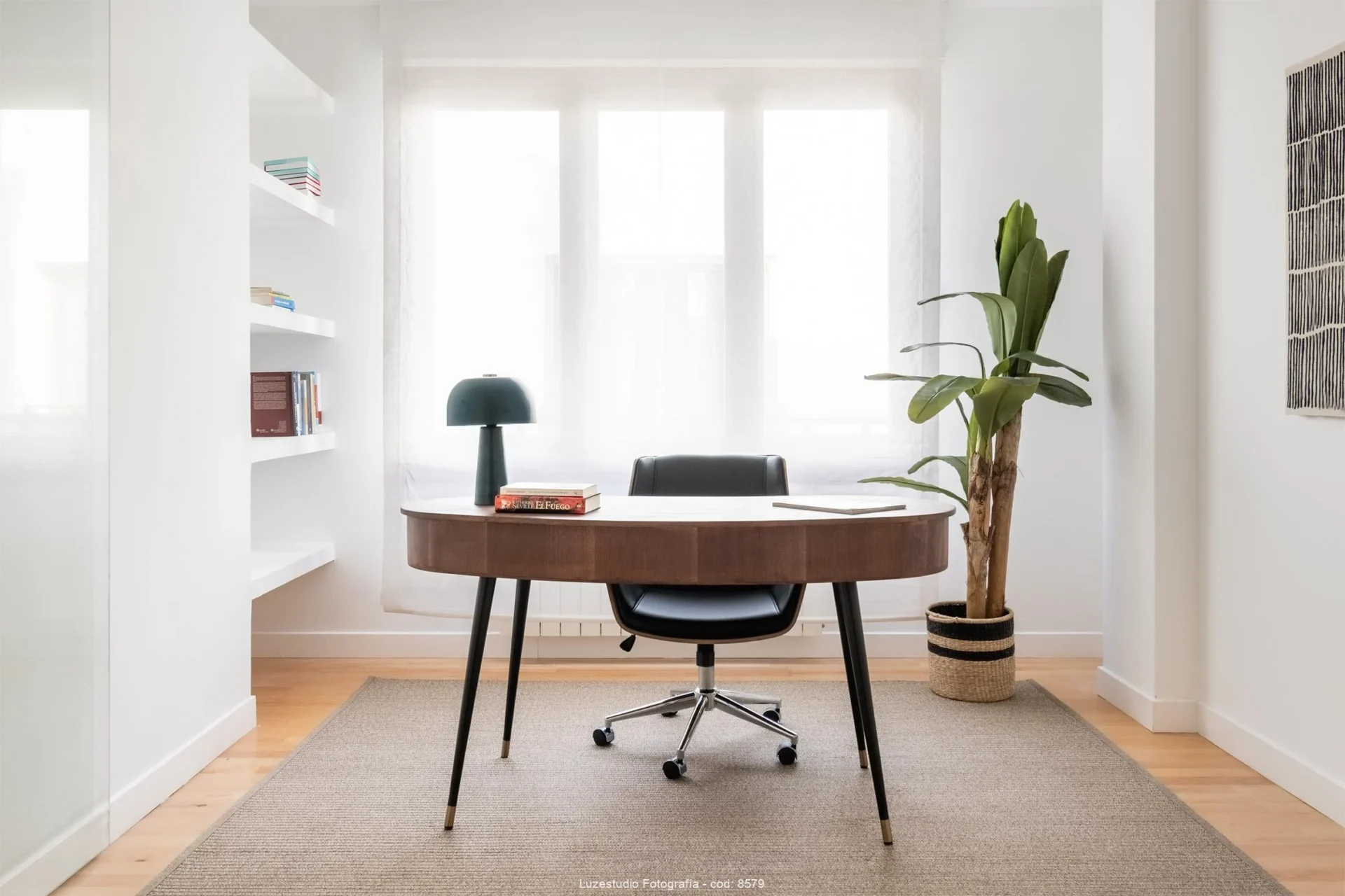 despacho con mesa de madera y silla de oficina con ruedas en habitacion con ventana y planta tropical