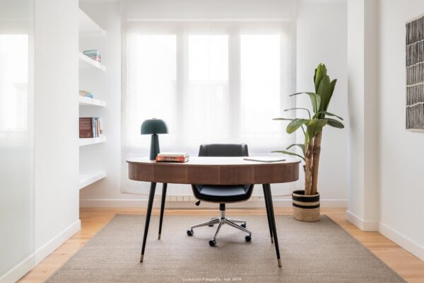 despacho con mesa de madera y silla de oficina con ruedas en habitacion con ventana y planta tropical