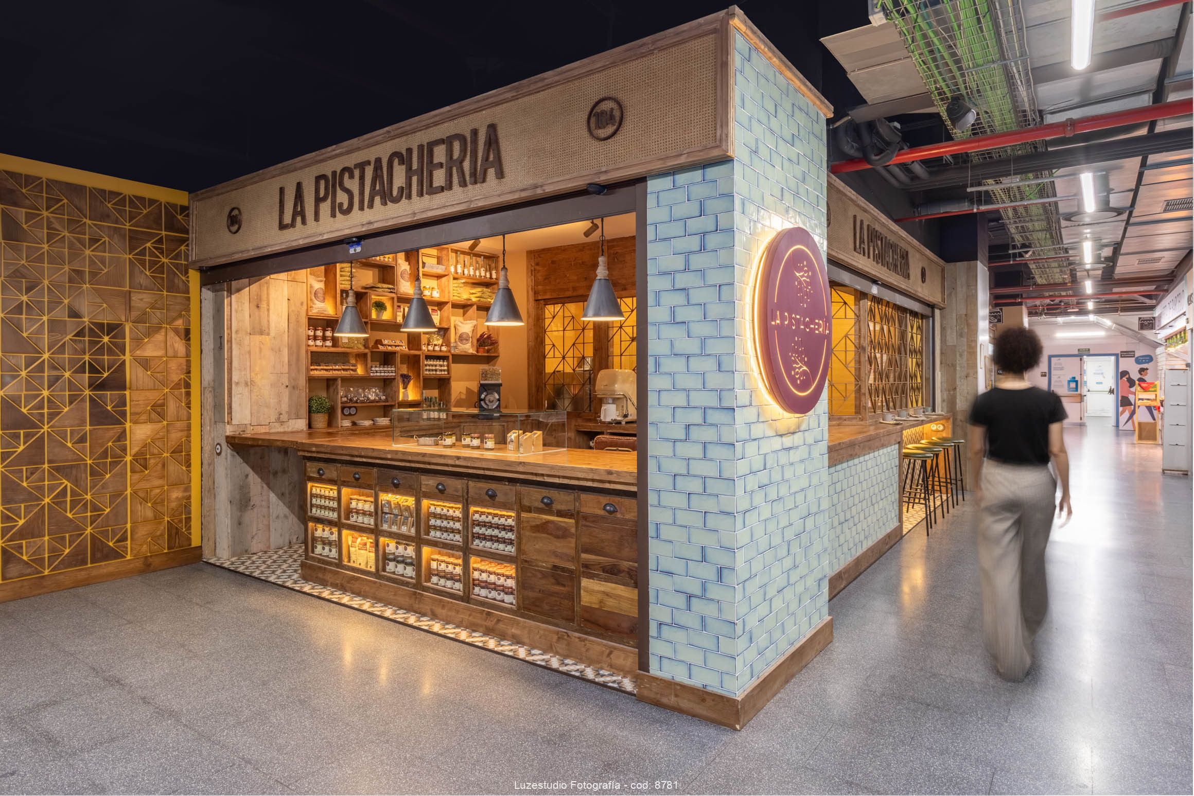 Local en Madrid por Fotografo de interiores Xerman Peñalver4 mujer de pelo corto con camiseta negra camina por pasillo de mercado berceló en madrid