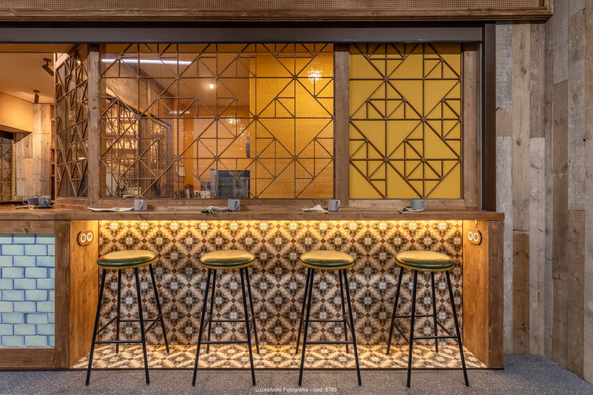 Local en Madrid por Fotografo de interiores Xerman Peñalver8 barra de madera en restaurante en mercado de madrid con cuatro sillas y pared de baldosa y madera