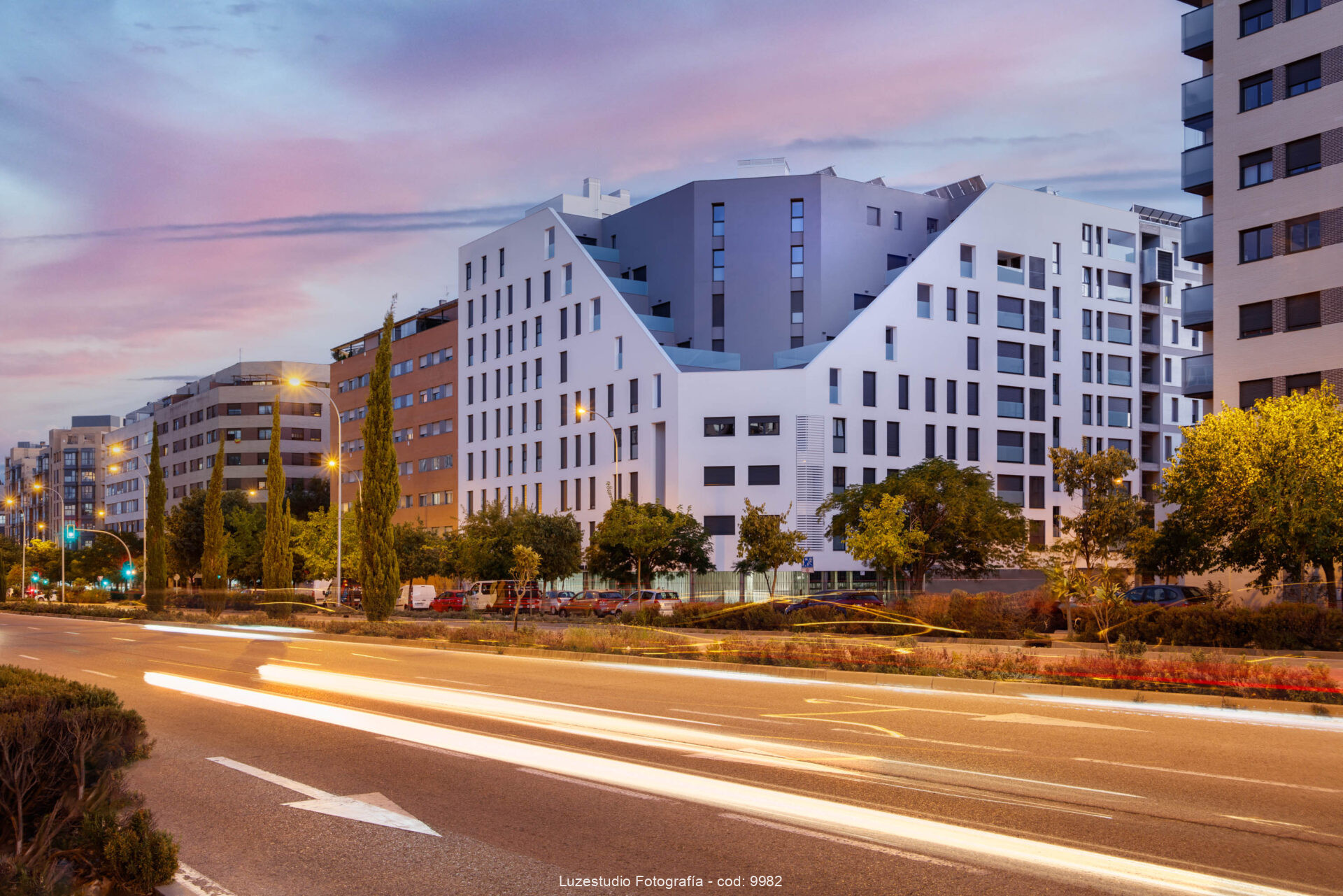fotografía de arquitectura obturación lenta al atardecer con edificio de viviendas y estelas de coches en la calle
