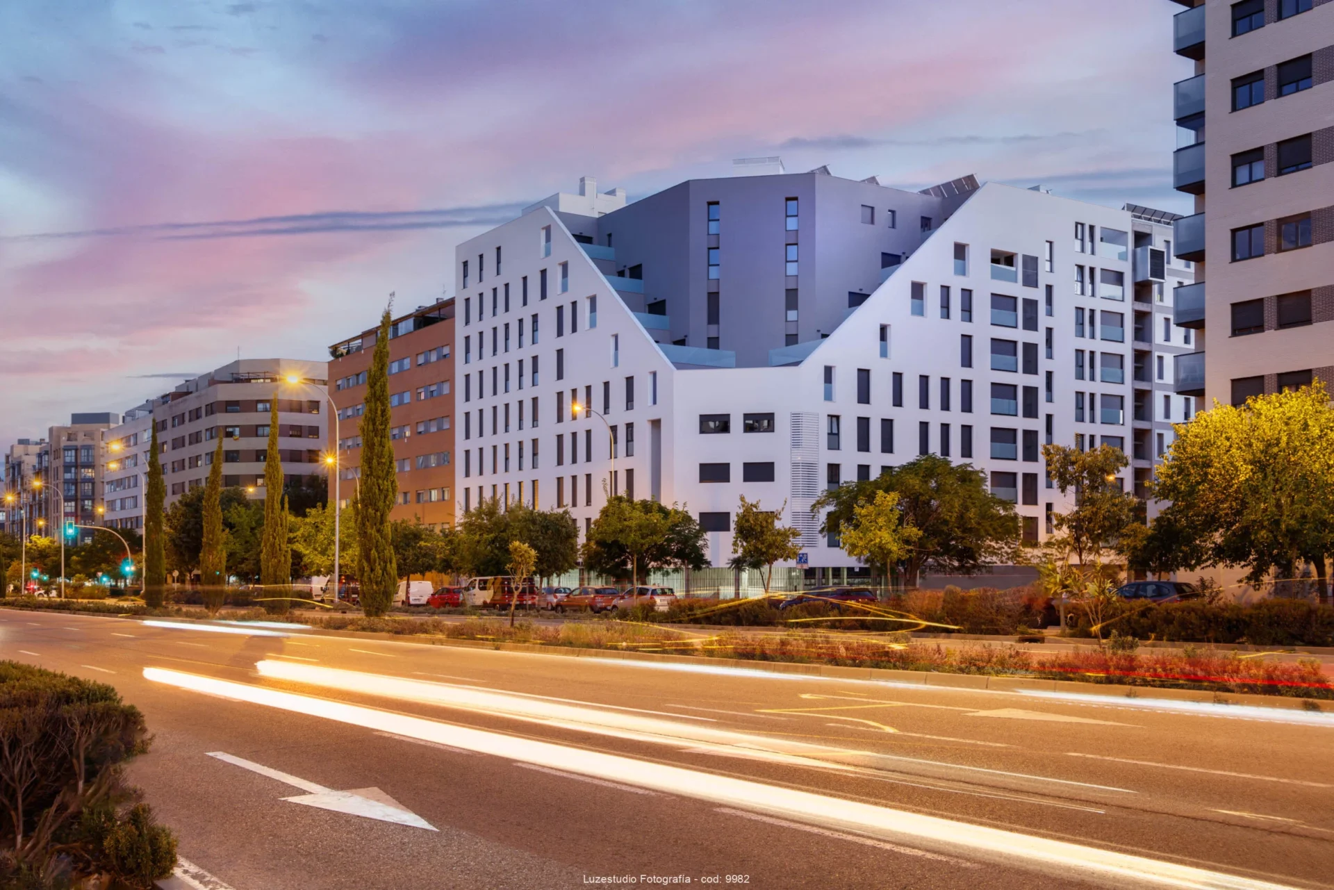 fotografía de arquitectura obturación lenta al atardecer con edificio de viviendas y estelas de coches en la calle