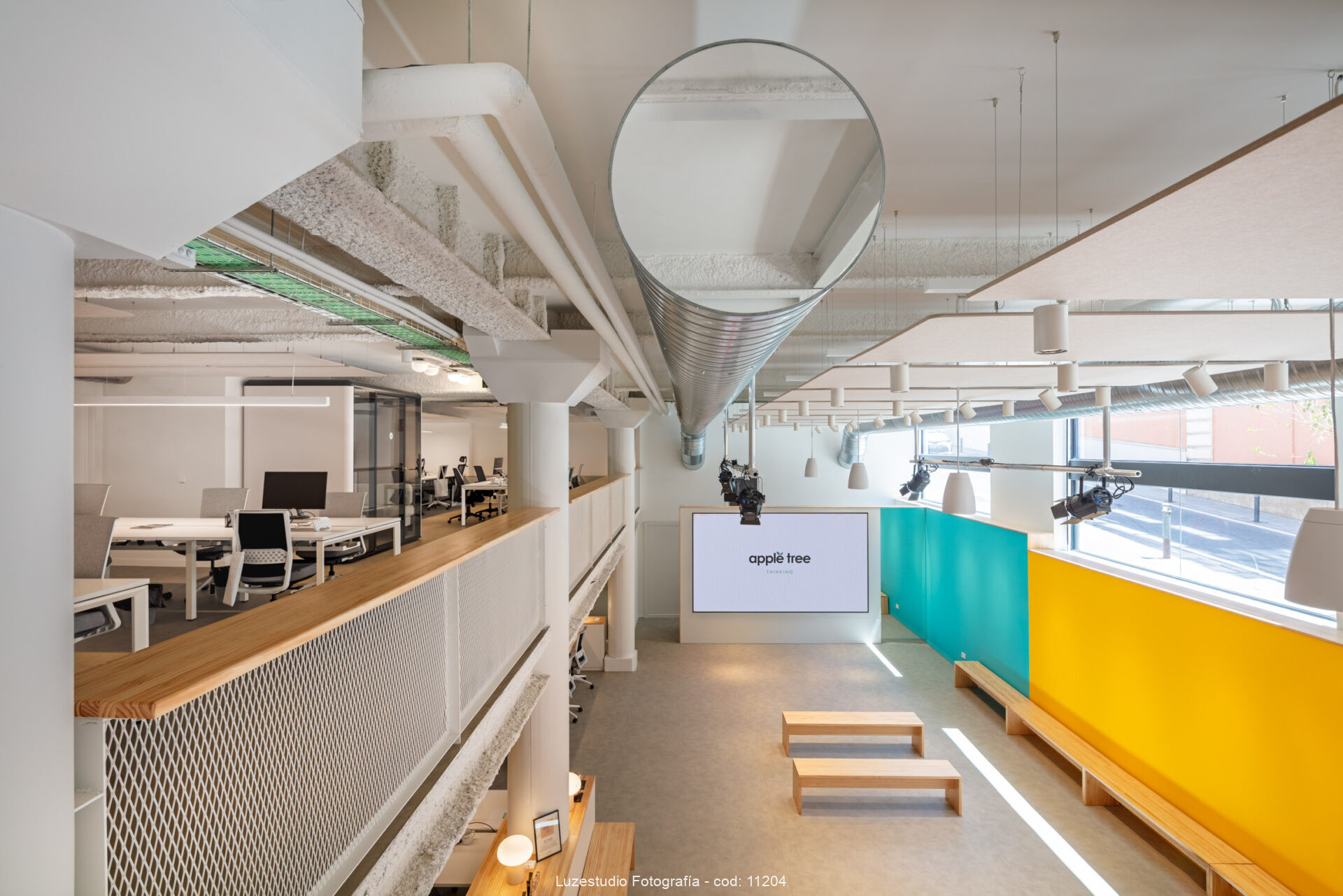 foto de espacio abierto con dos plantas en oficina moderna de madrid sala de proyecciones y mesas de espacio de trabajo con tuberia de climatización y espejo
